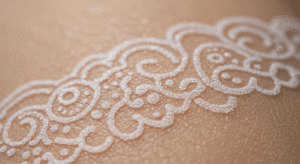 Close-up de uma tatuagem de renda feita com tinta branca cicatrizada na pele, mostrando seu efeito sutil e delicado.