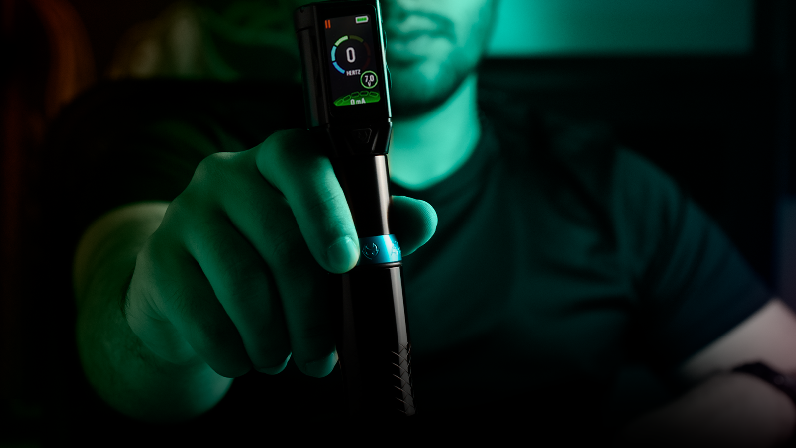 Mão de tatuador segurando uma máquina de tatuagem Electric Ink moderna, representando o serviço de assinatura Electric Ink Sempre.