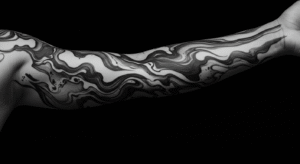 Braço com uma tatuagem de fechamento no estilo Suminagashi, com padrões abstratos que imitam a textura de mármore.