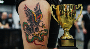 Tatuagem no estilo Old School de uma águia e uma cobra, com um troféu ao lado, representando a vitória em uma competição.