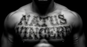 Tatuagem no peito masculino com a frase "Natus Vincere" em lettering chicano, ilustrando seu significado de força e vitória.