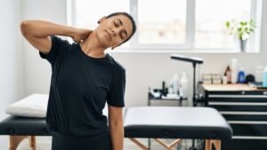 Tatuadora fazendo alongamentos para o pescoço em seu estúdio antes de uma sessão de tatuagem.